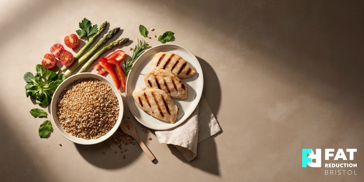 A tasteful overhead still-life of fresh vegetables, wholegrains and lean protein arranged on a warm neutral kitchen surface