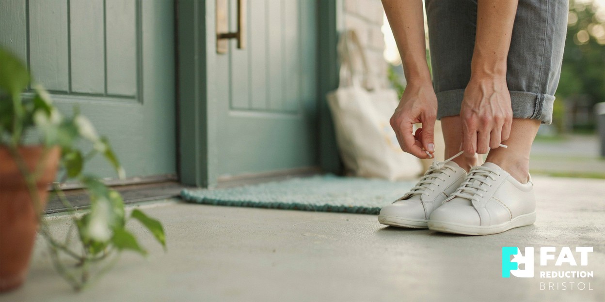 A person’s hands lacing up trainers on a doorstep before a morning walk, in soft natural daylight